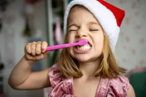 Smiles Dental, Day 10, Girl with Santa Hat brushing her teeth.